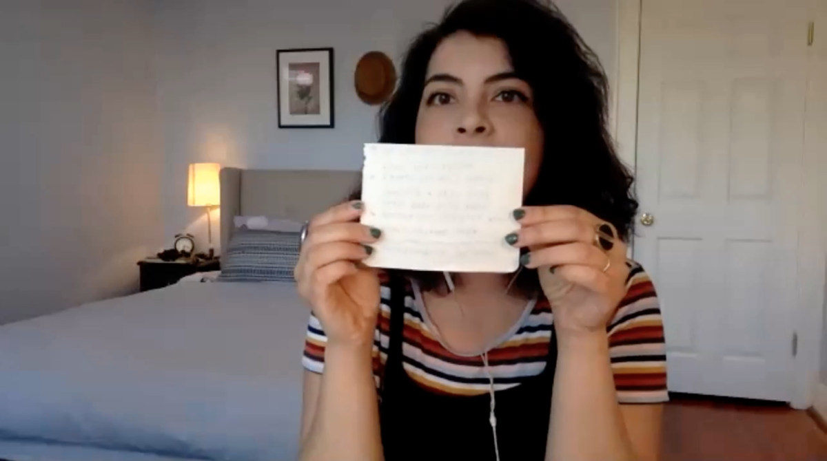 A young woman is holding a piece of paper that she has folded in half hamburger style.